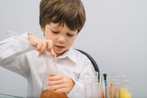 The boy with a microscope and various colorful flasks on a white background. A boy doing experiments in the laboratory. Explosion in the laboratory. Science and education photo