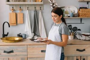 Young happy mom and her baby cook cookies at home in the kitchen. Christmas Homemade Gingerbread. cute boy with mother in white uniform and hat cooked chocolate cookies photo