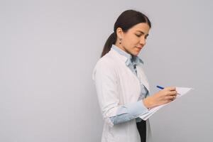 Female doctor in white uniform is holding flasks while standing against white background. photo