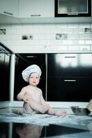 Little boy sitting on carpet in kitchen playing with cooking pots. Cute boy cooking in kitchen at home photo