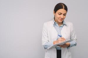 Female doctor in white uniform is holding flasks while standing against white background. photo