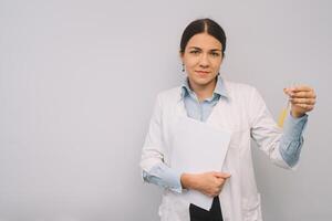 Female doctor in white uniform is holding flasks while standing against white background photo