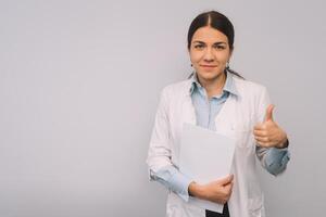 Female doctor in white uniform is holding flasks while standing against white background photo