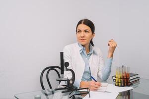 Beautiful medical doctors in gloves and glasses are working with substances in test tubes and microscope at the lab photo