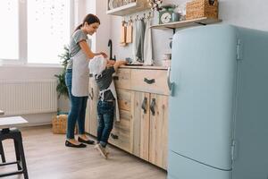 Young happy mom and her baby cook cookies at home in the kitchen. Christmas Homemade Gingerbread. cute boy with mother in white uniform and hat cooked chocolate cookies photo