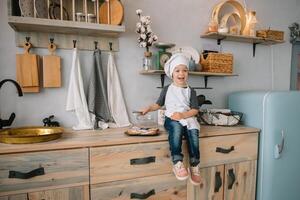 Young boy cute on the kitchen cook chef in white uniform and hat near table. Christmas homemade gingerbread. the boy cooked the chocolate cookies photo