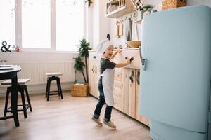 joven contento mamá y su bebé cocinar galletas a hogar en el cocina. Navidad hecho en casa pan de jengibre. linda chico con madre en blanco uniforme y sombrero cocido chocolate galletas. foto