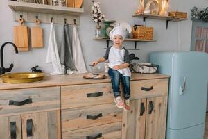 Young boy cute on the kitchen cook chef in white uniform and hat near table. Christmas homemade gingerbread. the boy cooked the chocolate cookies photo