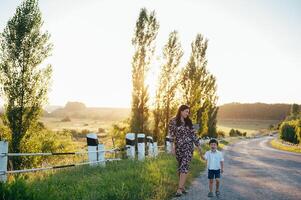 Stilish mother and handsome son having fun on the nature. Happy family concept. Beauty nature scene with family outdoor lifestyle. Happy family resting together. Happiness in family life. Mothers day. photo