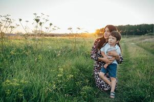 elegante madre y hermoso hijo teniendo divertido en el naturaleza. contento familia concepto. belleza naturaleza escena con familia al aire libre estilo de vida. contento familia descansando juntos. felicidad en familia vida. madres día foto