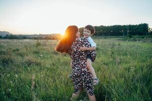 elegante madre y hermoso hijo teniendo divertido en el naturaleza. contento familia concepto. belleza naturaleza escena con familia al aire libre estilo de vida. contento familia descansando juntos. felicidad en familia vida. madres día foto