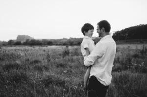 hermoso papá con su pequeño linda hijo son teniendo divertido y jugando en verde herboso césped. contento familia concepto. belleza naturaleza escena con familia al aire libre estilo de vida. familia descansando juntos. padres día. foto