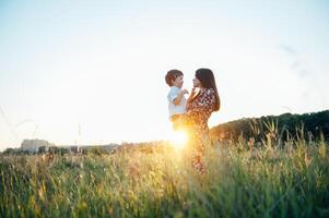 elegante madre y hermoso hijo teniendo divertido en el naturaleza. contento familia concepto. belleza naturaleza escena con familia al aire libre estilo de vida. contento familia descansando juntos. felicidad en familia vida. madres día foto