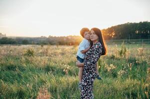 elegante madre y hermoso hijo teniendo divertido en el naturaleza. contento familia concepto. belleza naturaleza escena con familia al aire libre estilo de vida. contento familia descansando juntos. felicidad en familia vida. madres día foto