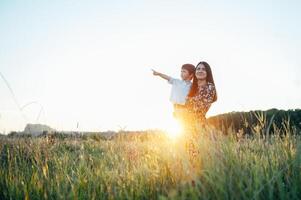 elegante madre y hermoso hijo teniendo divertido en el naturaleza. contento familia concepto. belleza naturaleza escena con familia al aire libre estilo de vida. contento familia descansando juntos. felicidad en familia vida. madres día foto