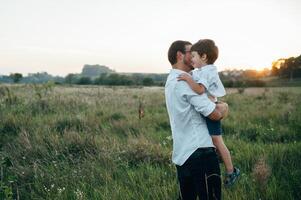 Handsome dad with his little cute son are having fun and playing on green grassy lawn. Happy family concept. Beauty nature scene with family outdoor lifestyle. family resting together. Fathers day. photo