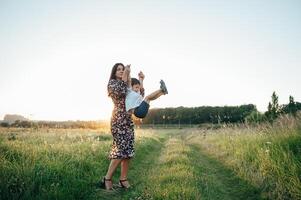 elegante madre y hermoso hijo teniendo divertido en el naturaleza. contento familia concepto. belleza naturaleza escena con familia al aire libre estilo de vida. contento familia descansando juntos. felicidad en familia vida. madres día foto