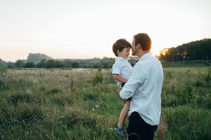 Handsome dad with his little cute son are having fun and playing on green grassy lawn. Happy family concept. Beauty nature scene with family outdoor lifestyle. family resting together. Fathers day. photo