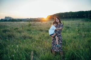 elegante madre y hermoso hijo teniendo divertido en el naturaleza. contento familia concepto. belleza naturaleza escena con familia al aire libre estilo de vida. contento familia descansando juntos. felicidad en familia vida. madres día foto