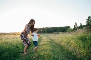 elegante madre y hermoso hijo teniendo divertido en el naturaleza. contento familia concepto. belleza naturaleza escena con familia al aire libre estilo de vida. contento familia descansando juntos. felicidad en familia vida. madres día foto