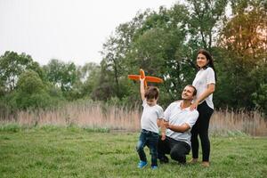 Father, mother and son playing with toy airplane in the park. friendly family. People having fun outdoors. Picture made on the background of the park and blue sky. concept of a happy family photo