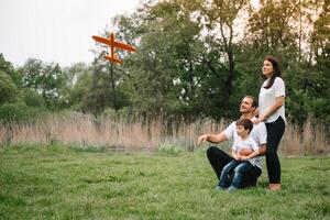 Father, mother and son playing with toy airplane in the park. friendly family. People having fun outdoors. Picture made on the background of the park and blue sky. concept of a happy family photo