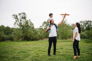 Father, mother and son playing with toy airplane in the park. friendly family. People having fun outdoors. Picture made on the background of the park and blue sky. concept of a happy family photo