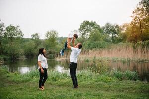 Happy family mother father and child son on nature on sunset. Mom, Dad and kid laughing and hugging, enjoying nature outside. Sunny day, good mood. concept of a happy family. photo