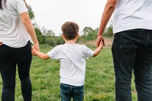 contento familia madre padre y niño hijo en naturaleza en puesta de sol. mamá, papá y niño riendo y abrazando, disfrutando naturaleza afuera. soleado día, bueno humor. concepto de un contento familia. foto