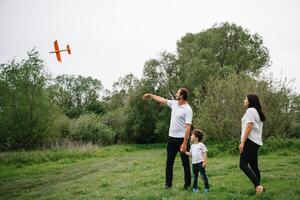 Father, mother and son playing with toy airplane in the park. friendly family. People having fun outdoors. Picture made on the background of the park and blue sky. concept of a happy family photo