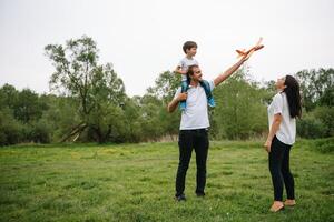 Father, mother and son playing with toy airplane in the park. friendly family. People having fun outdoors. Picture made on the background of the park and blue sky. concept of a happy family photo