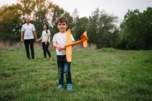 Father, mother and son playing with toy airplane in the park. friendly family. People having fun outdoors. Picture made on the background of the park and blue sky. concept of a happy family photo