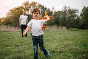 Father, mother and son playing with toy airplane in the park. friendly family. People having fun outdoors. Picture made on the background of the park and blue sky. concept of a happy family photo