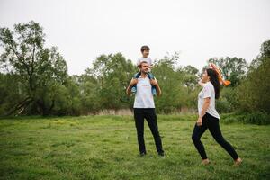 padre, madre y hijo jugando con juguete avión en el parque. simpático familia. personas teniendo divertido al aire libre. imagen hecho en el antecedentes de el parque y azul cielo. concepto de un contento familia foto