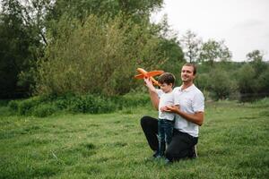 Father and son playing in aviator. Superman dad and son having fun. Imagination and dreams of being a pilot. Child pilot with airplane on dads back. Travel and vacation in summer. Freedom. photo