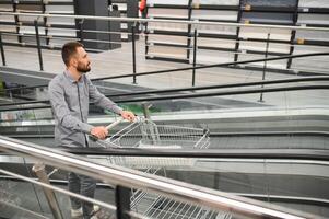 A man with a shopping cart on an escalator in a hardware store. photo