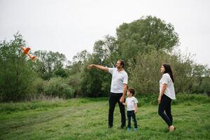 contento familia madre padre y niño hijo en naturaleza en puesta de sol. mamá, papá y niño riendo y abrazando, disfrutando naturaleza afuera. soleado día, bueno humor. concepto de un contento familia. foto