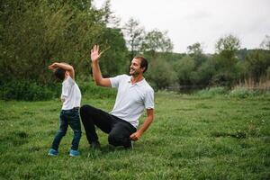 contento hombre y su niño teniendo divertido al aire libre. familia estilo de vida rural escena de padre y hijo en puesta de sol luz de sol. concepto de un contento familia. foto