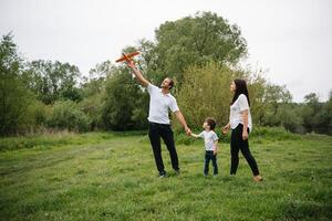 contento familia madre padre y niño hijo en naturaleza en puesta de sol. mamá, papá y niño riendo y abrazando, disfrutando naturaleza afuera. soleado día, bueno humor. concepto de un contento familia. foto