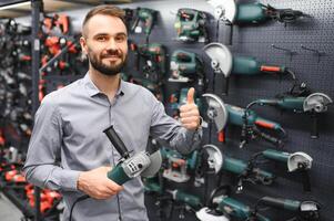 Confident smiling salesman on foreground in power tools store photo