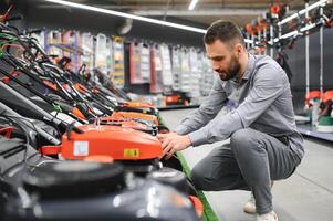 a customer examines new models of lawn mowers in an electrical store for gardeners and horticulturists photo