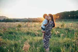 Stilish mother and handsome son having fun on the nature. Happy family concept. Beauty nature scene with family outdoor lifestyle. Happy family resting together. Happiness in family life. Mothers day photo