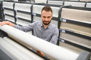 Male builder choosing wallpapers in hardware store photo