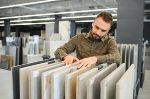 Man choosing tile among different samples in store photo