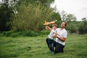 padre y hijo jugando en aviador. superhombre papá y hijo teniendo divertida. imaginación y Sueños de siendo un piloto. niño piloto con avión en papás atrás. viaje y vacaciones en verano. libertad. foto