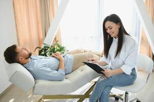 female psychologist making note while patient talking photo