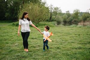 elegante madre y hermoso hijo teniendo divertido en el naturaleza. contento familia concepto. belleza naturaleza escena con familia al aire libre estilo de vida. contento familia descansando juntos. felicidad en familia vida. madres día foto