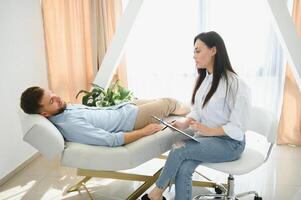 female psychologist making note while patient talking photo