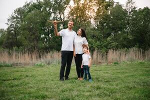 contento familia madre padre y niño hijo en naturaleza en puesta de sol. mamá, papá y niño riendo y abrazando, disfrutando naturaleza afuera. soleado día, bueno humor. concepto de un contento familia. foto