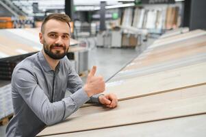 A young man chooses laminate flooring in the hardware store photo